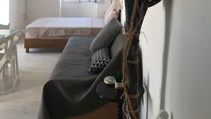 Una habitación con cama, sofá, televisión, ventana y techo con vigas de madera.