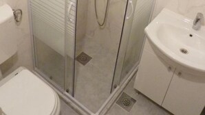 Ein Badezimmer mit Duschkabine, Waschbecken in Weiß und Toilette.