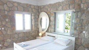Ein Schlafzimmer mit Stehwand, zwei Betten, einem großen Spiegel und einem Fenster mit Blick.