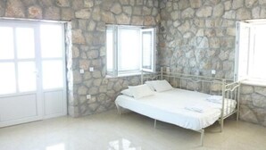 A bedroom with stone walls, a bed, a window, and a door. - 2-bedrooms apartment with AC (Dubrovnik)