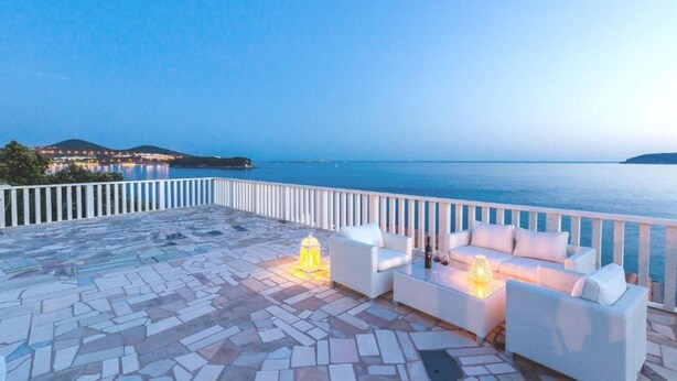 A terrace with a stone floor, white outdoor furniture, and a view of the sea. - 2-bedrooms apartment with AC (Dubrovnik)