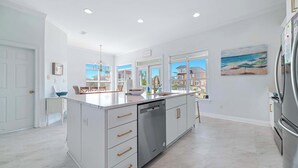 Una cucina moderna con isola centrale, mobili bianchi e frigorifero in acciaio inossidabile.