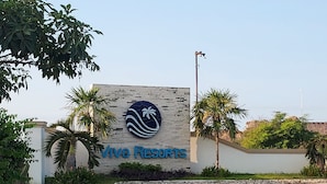 Señal de Vivo Resorts con logotipo, rodeada de palmeras y cielo despejado.