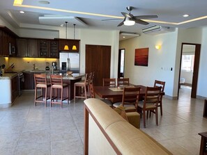 A modern kitchen with a dining area, wooden furniture, and a ceiling fan.