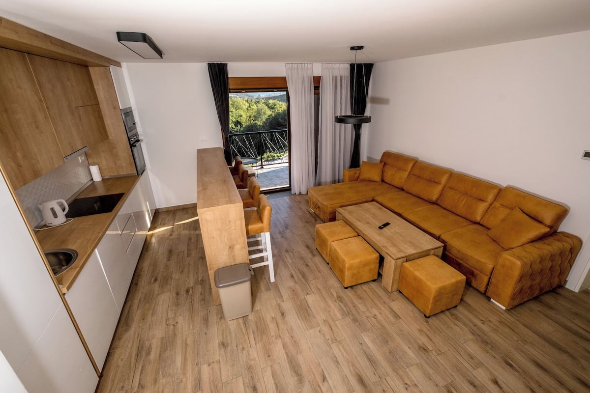 A modern living space with a kitchen, a sofa set, and a dining table.