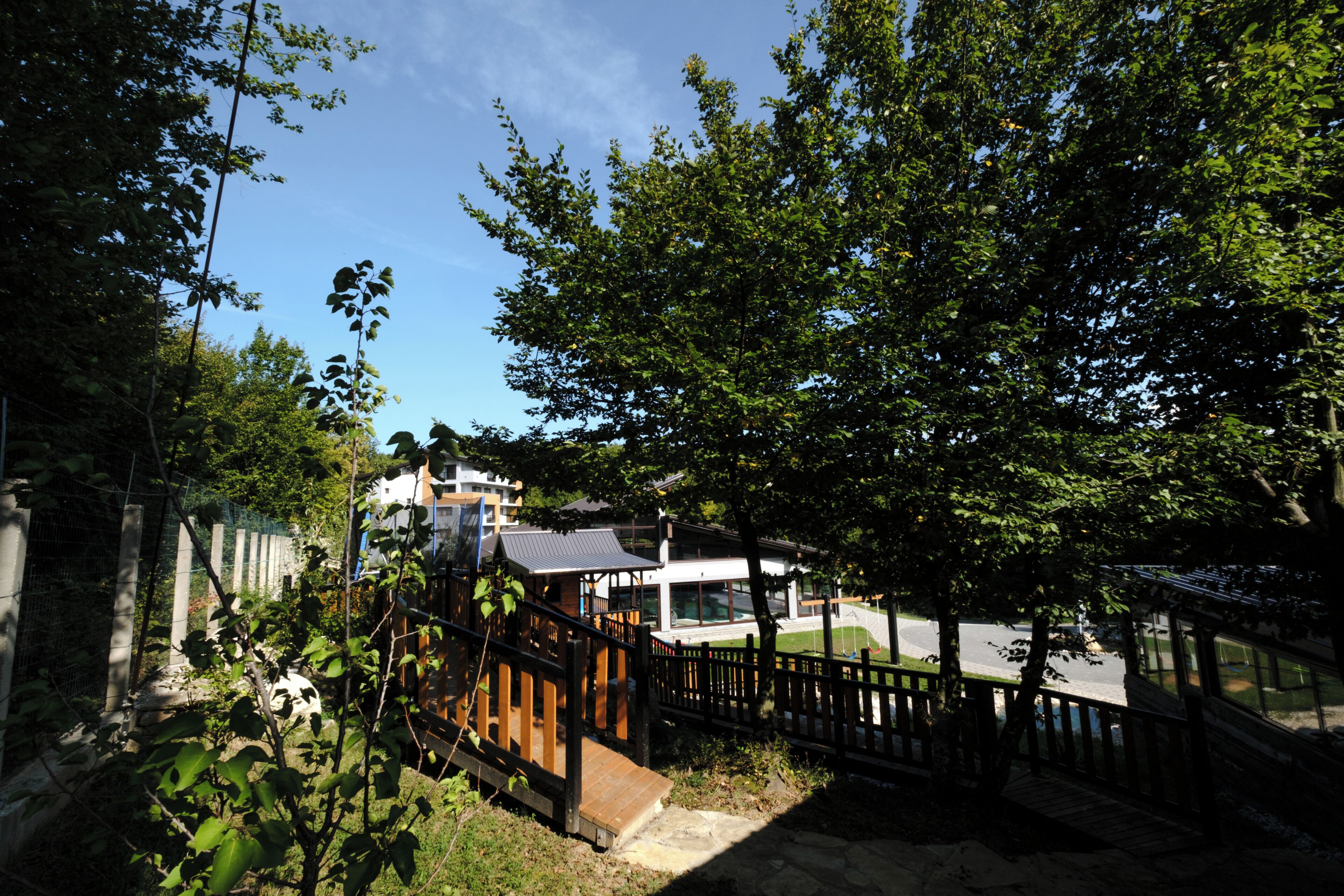 A residential area with a house, a wooden deck, and a fenced yard.