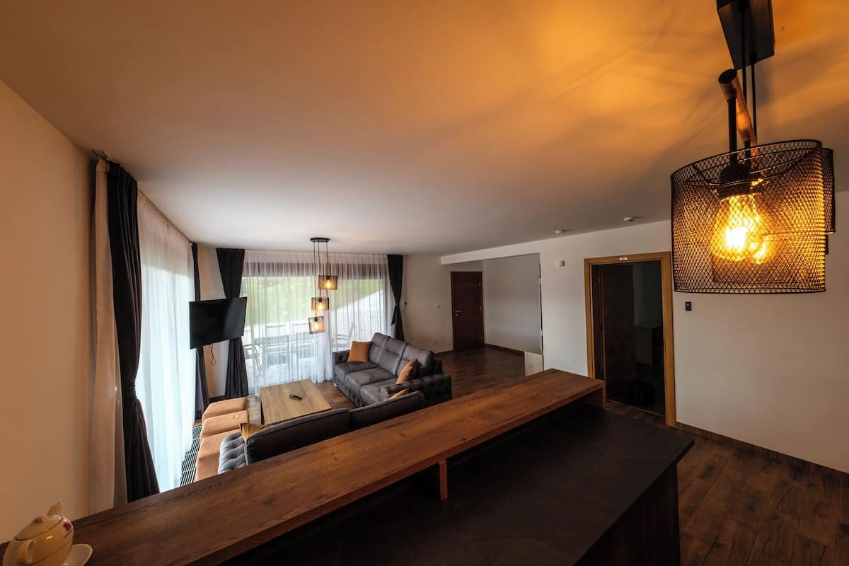 A modern living room with a sofa, a wooden coffee table, and a TV.