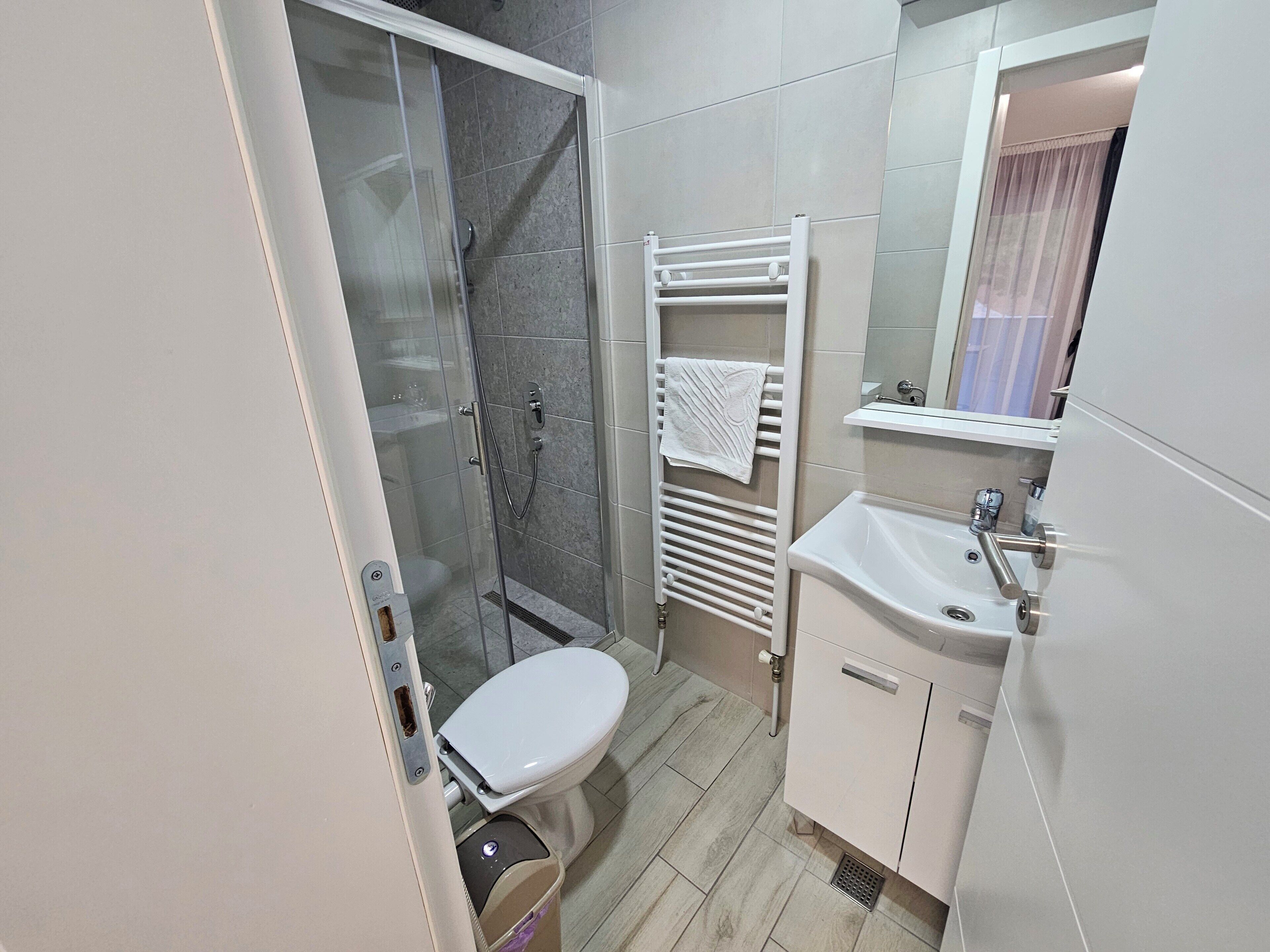 Une salle de bain équipée de toilettes, d’une douche, d’un lavabo et d’un porte-serviettes.