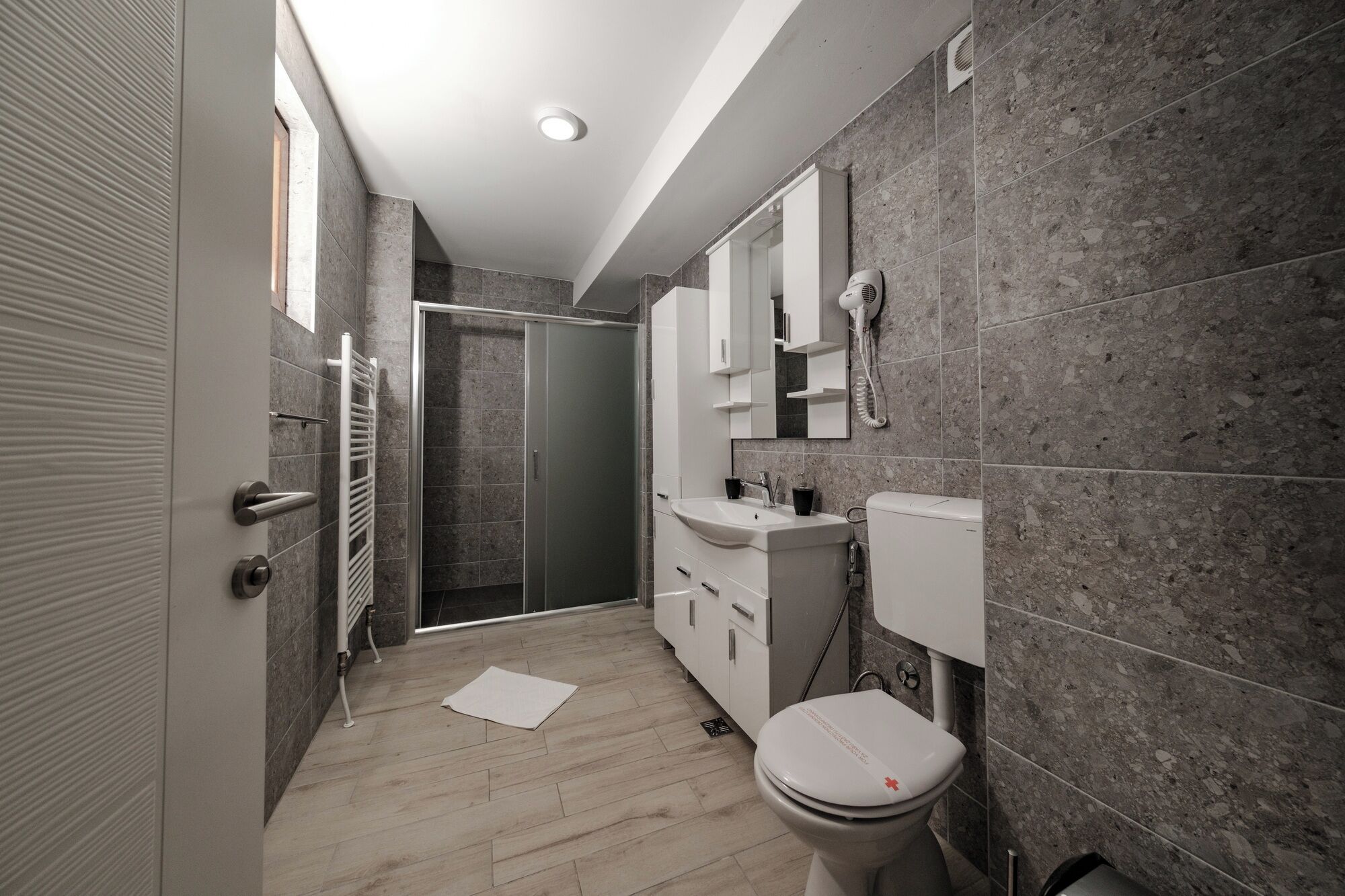 Een moderne badkamer met een douche, toilet en wastafel.