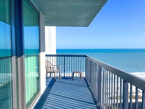 Ein Balkon mit Blick auf das Meer, ein Stuhl und ein Geländer.