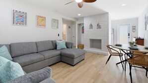 A modern living room with a grey sectional sofa, a dining table with chairs, a white fireplace, and ceiling fans. - A&B Two Apt in a Triplex with 4 bedrooms and 2 bathrooms Near the Beach and 5th (Naples)