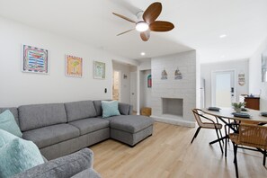 A modern living room with a grey sectional sofa, a dining table with chairs, a white fireplace, and ceiling fans. - A&B Two Apt in a Triplex with 4 bedrooms and 2 bathrooms Near the Beach and 5th (Naples)