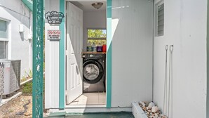 A laundry room with a washing machine, a sign prohibiting smoking and vaping, and a small shelf with cleaning supplies. - A&B Two Apt in a Triplex with 4 bedrooms and 2 bathrooms Near the Beach and 5th (Naples)