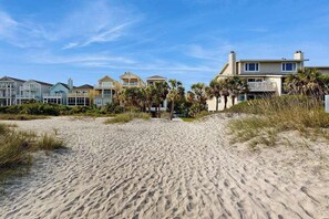 A beachfront property with multiple houses, sandy beach, and palm trees. - Lagoon-View Villa Steps from the Beach (Isle of Palms)