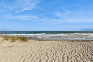 A beach with sand and waves, clear sky, and distant horizon. - Lagoon-View Villa Steps from the Beach (Isle of Palms)