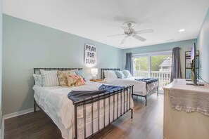 A bedroom with two beds, a ceiling fan, a window with curtains, and a sign on the wall. - Lagoon-View Villa Steps from the Beach (Isle of Palms)
