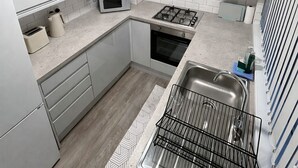 Uma cozinha moderna com armários brancos, micro-ondas, fogão e pia.
