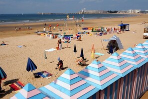 A beach with umbrellas, beach chairs, and a lifeguard stand.