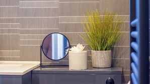 Un mobile bagno con specchio, carta igienica e una pianta in vaso.
