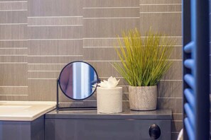 Ein Badezimmer-Waschtisch mit Spiegel, Toilettenpapier und einer Topfpflanze.