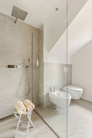 Ein modernes Badezimmer mit Duschkabine aus Glas, freistehender Badewanne und Toilette.