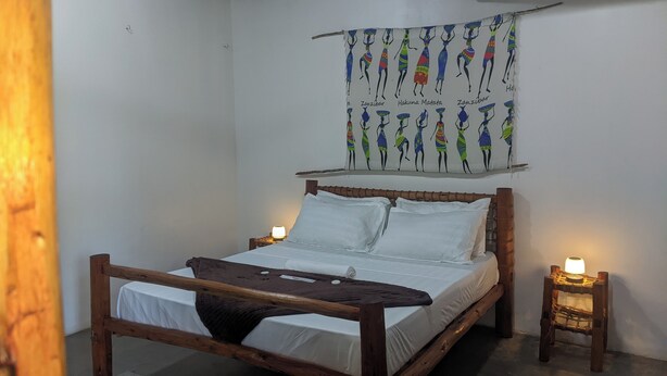 Un lit avec du linge de lit blanc, une tête de lit en bois et deux lampes de chevet.