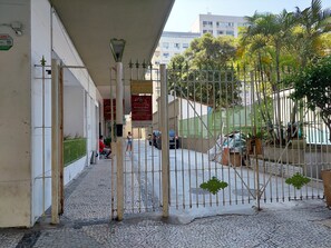 A paved walkway with a metal gate, a street lamp, and a building with a sign. - Studio 5 minutes from Copacabana and Ipanema beaches (Rio de Janeiro)