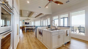 A spacious kitchen with a large island, wooden flooring, and a view to the outside. - Sea Time: 4 BR, 3 BA House in Crystal Beach, Sleeps 12 (Crystal Beach)