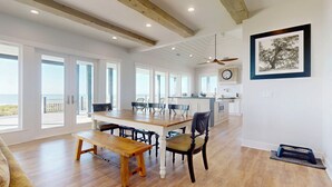 Ein geräumiger Essbereich mit Holztisch und Stühlen, einer Bank, einem Deckenventilator und einer Küche im Hintergrund.