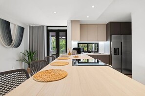 A modern kitchen with a long island, dark cabinets, and a stainless steel refrigerator. - Luxe Yunque Retreat | Pool & Beach Access (Río Grande)