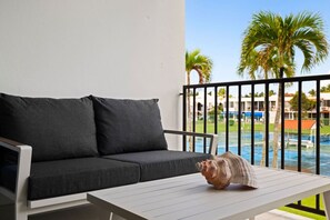 A balcony with a black sofa, a white table, and a seashell decoration. - Luxe Yunque Retreat | Pool & Beach Access (Río Grande)