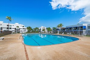 A swimming pool with clear blue water, surrounded by a sandy deck and a fence. - Luxe Yunque Retreat | Pool & Beach Access (Río Grande)