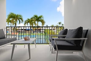 A balcony with a pool view, outdoor seating, and a clear sky. - Luxe Yunque Retreat | Pool & Beach Access (Río Grande)