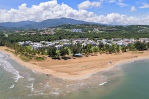 A coastal resort with beachfront villas, a sandy beach, and a mountainous backdrop. - Luxe Yunque Retreat | Pool & Beach Access (Río Grande)