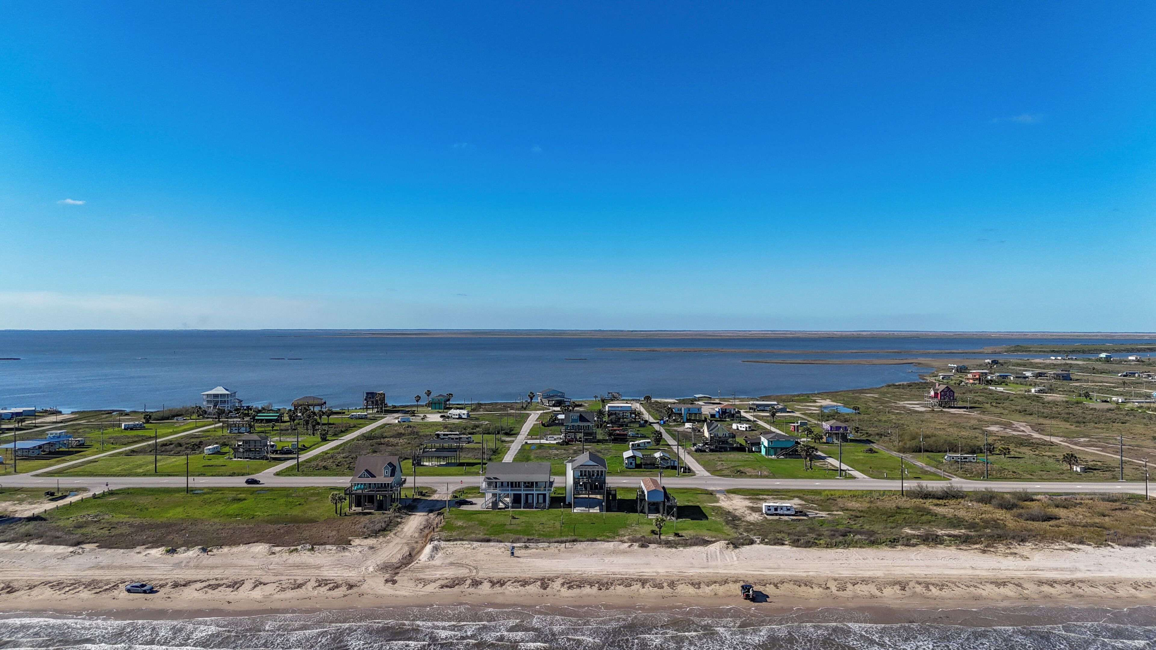 Ett bostadsområde vid kusten med hus, en strand och en fri utsikt över havet.