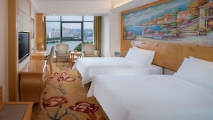 A hotel room with two beds, a TV, a desk, and a painting of a coastal scene. - Vienna International Hotel - Dayong city (Zhangjiajie)