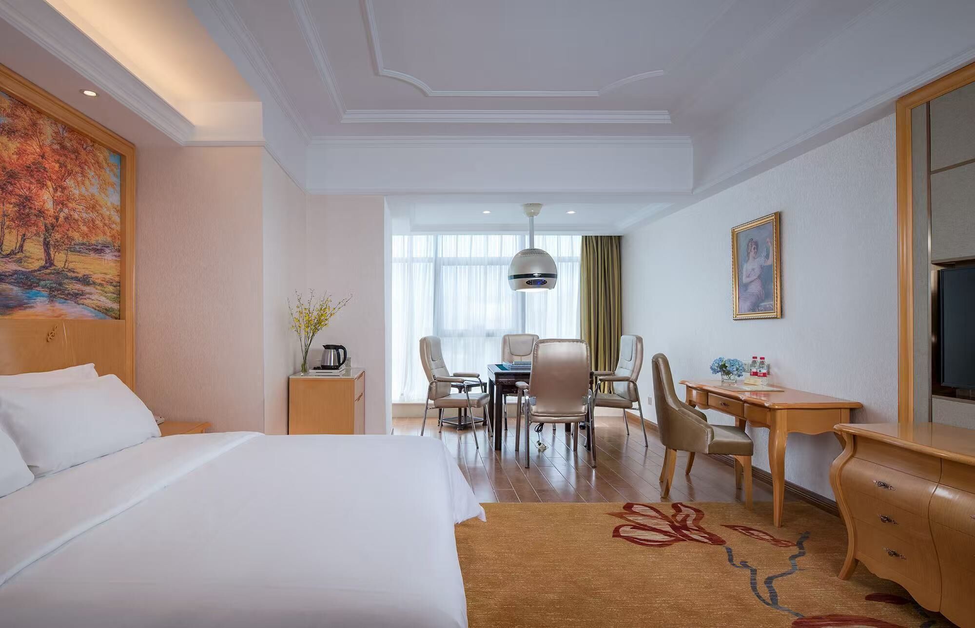 Una camera d'albergo con un letto, una scrivania, delle sedie, un tavolo da pranzo e un'ampia finestra.