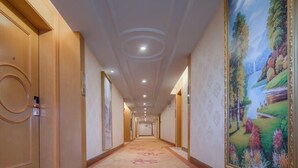 A hallway with a carpeted floor, wooden doors, and a large landscape painting on the wall. - Vienna International Hotel - Dayong city (Zhangjiajie)