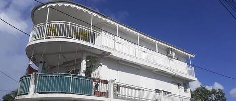 A multi-story building with balconies, a satellite dish, and a clear blue sky.