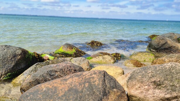 A rocky shoreline with clear water and a distant view of the sea. - Holiday Home 'Cupedia' with Wi-Fi (Schwedeneck)