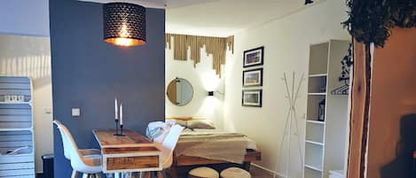 Ein modernes Interieur mit einem Holztisch, weißen Stühlen, einem runden Spiegel und einer Pendelleuchte.