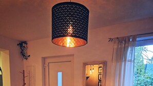A dining area with a wooden table, a bicycle storage unit, a hanging light fixture, a door, and a window with curtains. - Holiday Home 'Cupedia' with Wi-Fi (Schwedeneck)