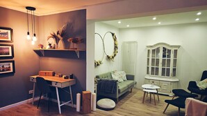 A room with a wooden desk, a green sofa, a white cabinet, and a dining table. - Holiday Home 'Cupedia' with Wi-Fi (Schwedeneck)