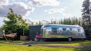A silver trailer with a small attached structure, a hammock, and a wooden fence in a grassy area. - Sleeps 2 - Hot Tub - Pet Friendly - Peggysue (Skegness)
