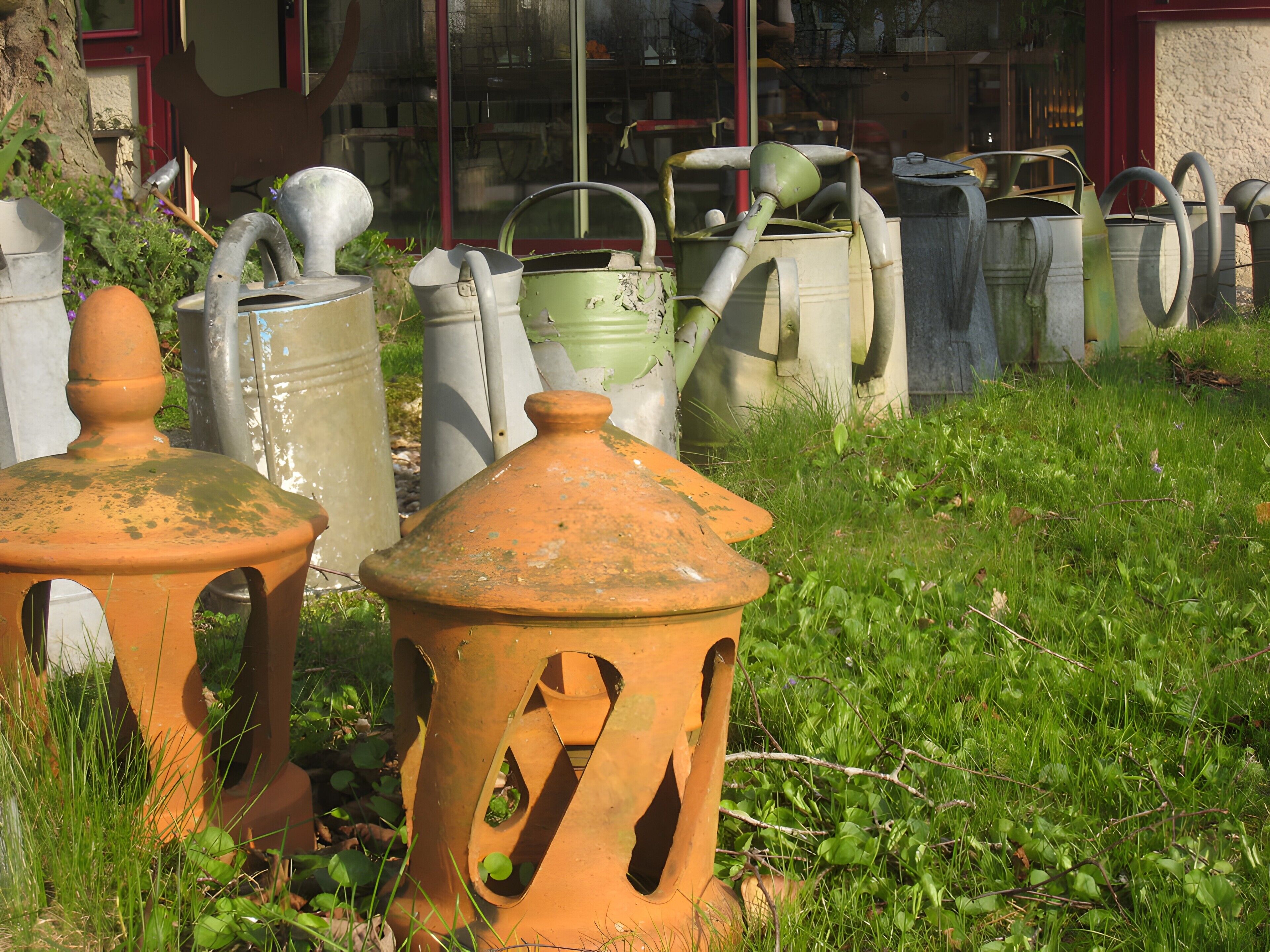 A collection of outdoor garden furniture, including pots and chairs, arranged on a grassy area.