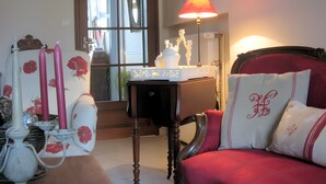 Una habitación con un sofá rojo, una mesa con una lámpara y un espejo con vista al exterior.