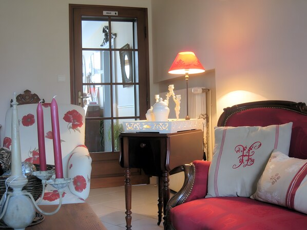 Una habitación con un sofá rojo, una mesa con una lámpara y un espejo con vista al exterior.