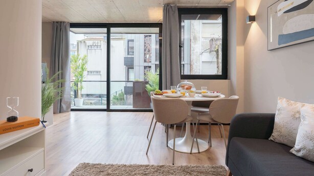 Un salon moderne comprenant un coin repas, un canapé, une table basse et offrant une vue sur la ville grâce à de grandes fenêtres.
