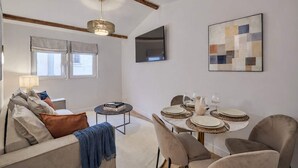 A modern living room with a dining area, a flat-screen TV mounted on the wall, and a contemporary abstract painting. - Beautiful Renovated Apartment With AC - Paris East (Paris)