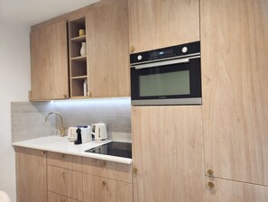 A kitchen with wooden cabinets, a built-in oven, a sink, and a toaster. - Beautiful Renovated Apartment With AC - Paris East (Paris)